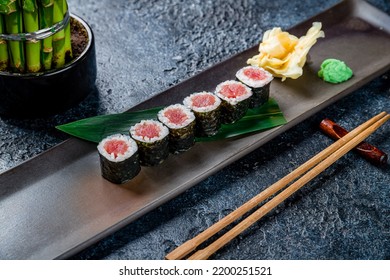 roll with tuna maki on dark plate on dark stone table