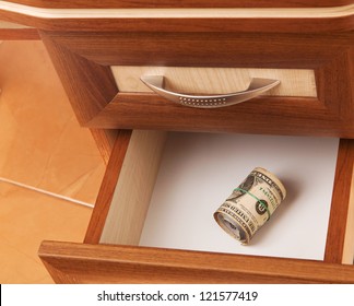roll of United States dollars in open desk  drawer