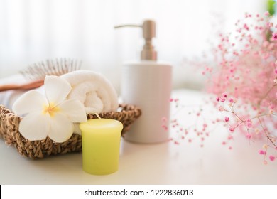 Roll Up Of White Towels And Comp On Basket, Ceramic Soap, Shampoo Bottles On White Table With Copy Space On Blurred Living Room Background. For Product Display Montage.