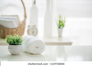 Aufrollen weißer Handtücher auf weißem Tisch mit Kopienraum auf unscharfem Wohnzimmerhintergrund. Für Produktdarstellung-Montage.