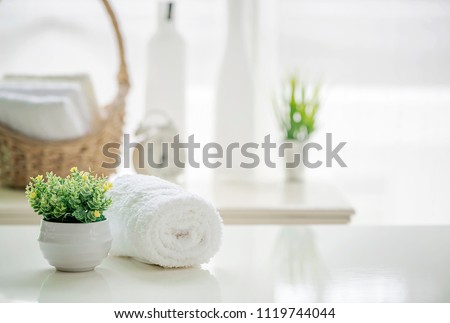 Roll up of white towels on white table with copy space on blurred living room background. For product display montage.