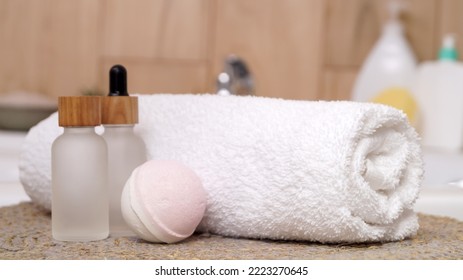 Rolled Bath Towel And Different Cosmetic Products On Table In Bathroom, Closeup