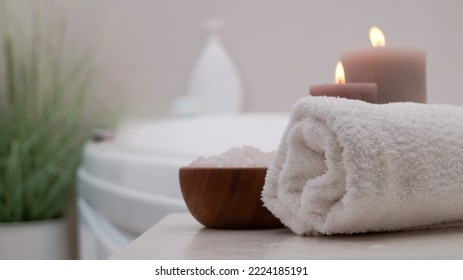 Rolled Bath Towel, Sea Salt And Burning Candles On Table In Bathroom, Closeup. Space For Text