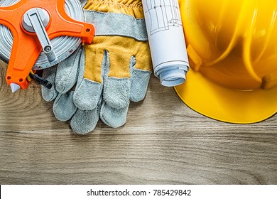 Rolled blueprints safety gloves measuring tape building helmet on wooden board. - Shutterstock ID 785429842