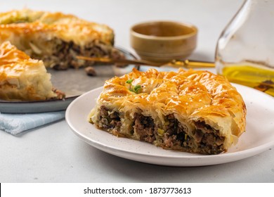 Rolled Burek - savoury pie fith meat and mushrooms feeling, decorated with sesam seedes. Peace of pie on a white table. - Shutterstock ID 1873773613