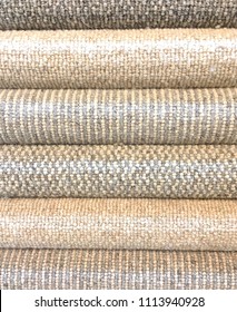 Rolled Carpet samples on display in a carpet shop with a variety of brown to beige colour options and textures in a full frame vertical format. 