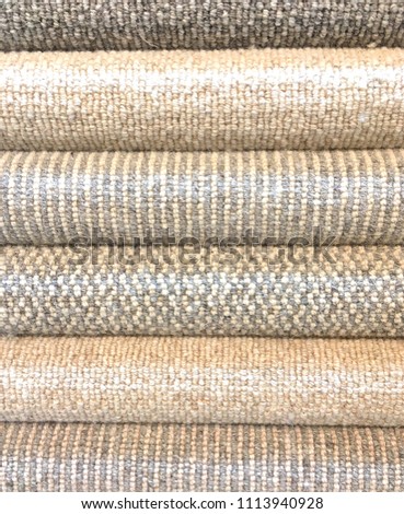 Rolled Carpet samples on display in a carpet shop with a variety of brown to beige colour options and textures in a full frame vertical format. 
