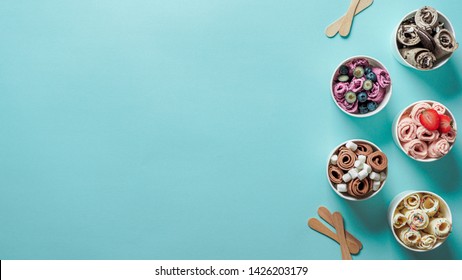 rolled ice creams in cone cups on blue background. Different iced rolls top view or flat lay. Thai style rolled ice cream with copy space for text or design. Banner