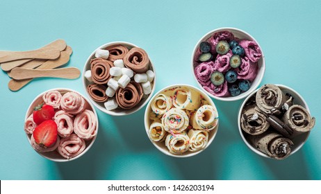 rolled ice creams in cone cups on blue background. Different iced rolls top view or flat lay. Thai style rolled ice cream