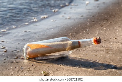 Rolled Letter Inside Glass Bottle On A Beach
