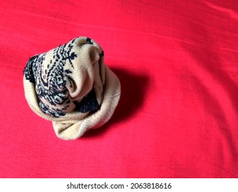 a rolled up light brown sock, on a red background isolated