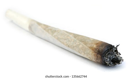 A rolled marijuana joint half burnt, isolated on white.