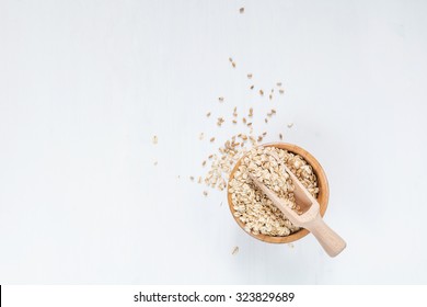 Rolled Oats In Bowl On White Table, Top View. Copy Space