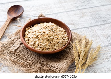 Rolled oats, healthy breakfast cereal oat flakes in bowl on wooden table - Shutterstock ID 653741836
