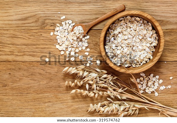 Rolled oats and oat ears of grain on a wooden
table, copy space