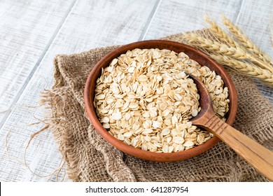 Rolled oats, oat flakes, uncooked oats in bowl with wooden spoon and wheat ears. Concept of healthy eating, vegan food, healthy food, breakfast.