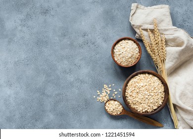 Rolled oats, oat flakes, whole grain oats in wooden bowl, linen textile and golden ears of wheat on concrete background with copy space for text - Powered by Shutterstock