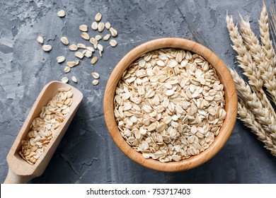 Rolled oats or oat flakes in wooden bowl and golden wheat ears on stone background. Top view, horizontal. Healthy lifestyle, healthy eating, vegan food concept - Powered by Shutterstock