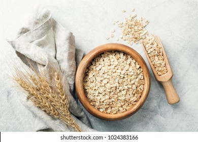 Rolled Oats In Wooden Bowl And Ears Of Wheat On Grey Background. Table Top View. Healthy Eating, Healthy Lifestyle, Gluten Free Diet Concept