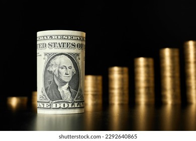 Rolled one dollar bill on the background of stacks of coins - Shutterstock ID 2292640865