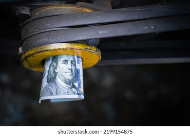 A Rolled One Hundred Dollar Bill Close-up In A Tractor Engine Pulley. Funding For Agricultural Land. The Cost Of Maintenance And Production On The Farm. Purchase And Repair Of Agricultural Machinery