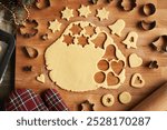 Rolled out pastry dough with cut out shapes on a wooden board - preparation of homemade Linzer cookies, top view