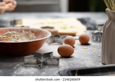 Rolled out puff pastry and molds for baking cookies, eggs, wooden rolling pin, spilled flour, a jug with ears of wheat on a black table in the kitchen. selective focus - Powered by Shutterstock