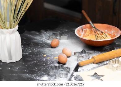 Rolled Out Puff Pastry And Molds For Baking Cookies, Eggs, Wooden Rolling Pin, Spilled Flour, A Jug With Ears Of Wheat On A Black Table In The Kitchen. Selective Focus