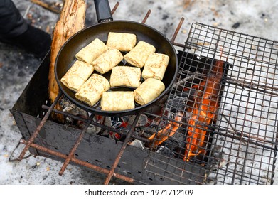 rolled pancakes with filling are fried in a frying pan on the fire in the grill. winter cooking food in nature outdoor. traditional national russian folk dish for the celebration of maslenitsa