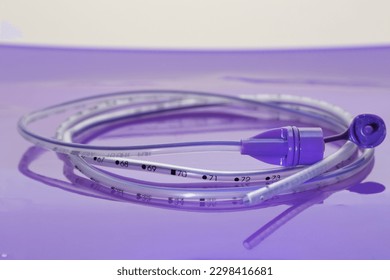 Rolled up polyurethane enteral feeding tube for nasal or oral gastric placement to provide nutrition, fluid and medication to neonatal and pediatric patients on lilac background - Shutterstock ID 2298416681