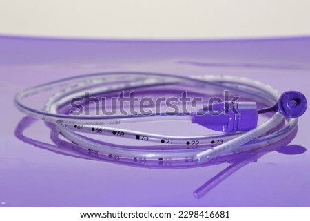 Rolled up polyurethane enteral feeding tube for nasal or oral gastric placement to provide nutrition, fluid and medication to neonatal and pediatric patients on lilac background