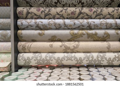 Rolled up rolls of vinyl wallpaper. Different textures and colors, as background. Beige, gray wallpaper with floral pattern for the wall. Decorative  materials for renovation of room, interior