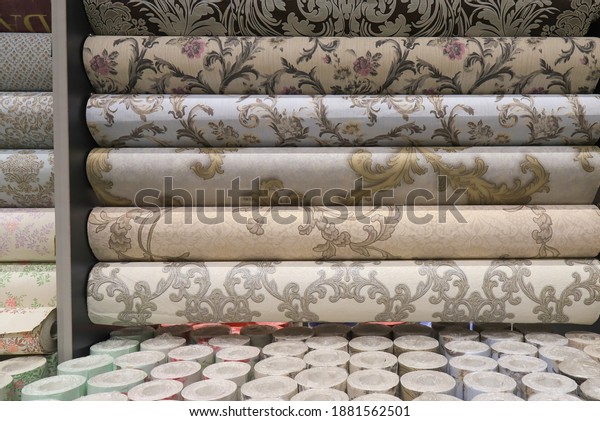 Rolled up rolls of vinyl wallpaper. Different\
textures and colors, as background. Beige, gray wallpaper with\
floral pattern for the wall. Decorative  materials for renovation\
of room, interior