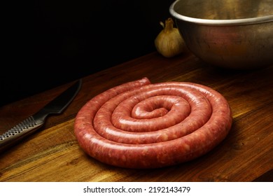 Rolled Sausage Luganega On Wooden Cutting Board. Pork, Typical Italian Sausage