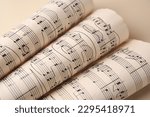 Rolled sheets with music notes on light background, closeup