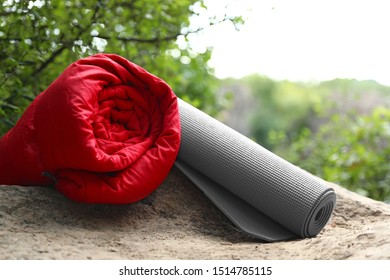 Rolled sleeping bag and mat on rock - Powered by Shutterstock