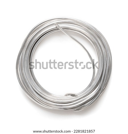 Rolled up soft solder wire. Fusible metal alloy with 60 percent tin, used to create a permanent bond between metal workpieces and for electrical connections. Close up, from above, on white background.