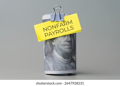 A rolled stack of US one-hundred dollar bills with a note 