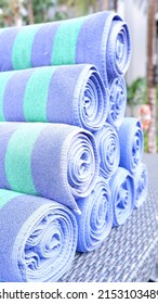 Rolled towels at the edge of the pool used to dry the body after swimming. A towel is a piece of cloth or paper that can absorb liquid and is used for wiping or drying.