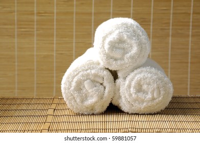 Rolled Up White Spa Towel On Woven Mat Background