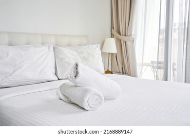 Rolled Up White Towels On The Hotel Bed.