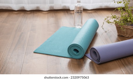 A rolled up yoga mat and water. Do yoga in the room. - Powered by Shutterstock