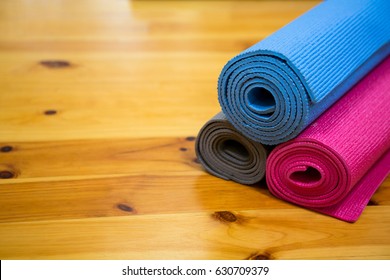 Rolled-up Exercise Mat On Wooden Floor In Gym