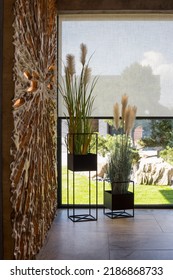 Roller Blinds In The Interior. Automatic Solar Shades Large Size On The Window. Modern Interior With Wood Decor Panel On The Wall. Green Plants In Hi-tech Flower Pots. Electric Curtains For Home. 