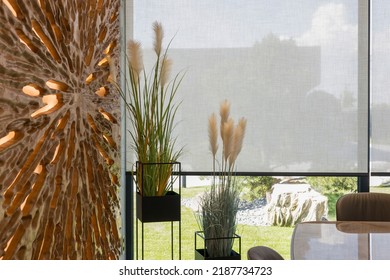 Roller Blinds In The Interior. Automatic Solar Shades Large Size On The Window. Modern Interior With Wood Decor Panel On The Wall. Green Plants In Hi-tech Flower Pots. Electric Curtains For Home. 