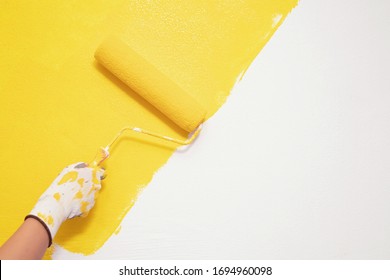 Roller Brush Painting, Worker painting on surface wall  Painting apartment, renovating with yellow color  paint. Leave empty copy space white to write descriptive text beside. - Shutterstock ID 1694960098