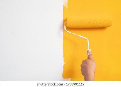 Roller Brush Painting, Worker painting on surface wall  Painting apartment, renovating with yellow color  paint. Leave empty copy space white to write descriptive text beside.