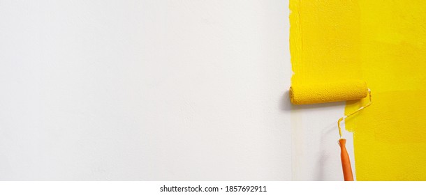 Roller Brush Painting, Worker painting on surface wall  Painting apartment, renovating with yellow color  paint. Leave empty copy space white to write descriptive text beside.