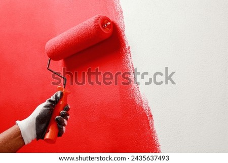 Roller Brush Painting, Worker painting on surface wall  Painting apartment, renovating with red color  paint. Leave empty copy space white to write descriptive text beside.