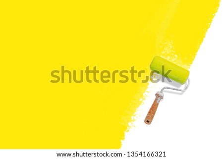 roller brush with yellow painted wall - colorful renovation concept 